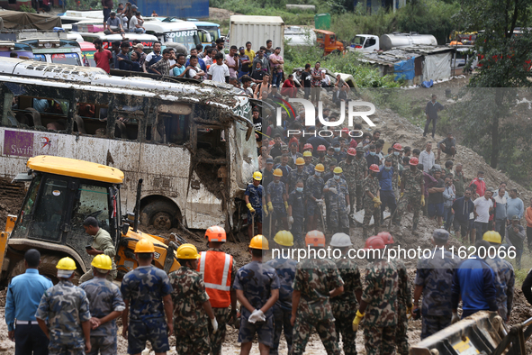 Personnel from Nepal's security agencies, the Nepal Army, Armed Police Force, and the Nepal Police continue a search operation at a landslid...