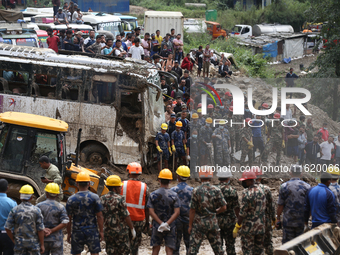 Personnel from Nepal's security agencies, the Nepal Army, Armed Police Force, and the Nepal Police continue a search operation at a landslid...