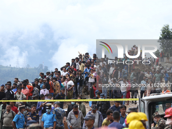 Locals and relatives of the missing passengers gather at Jhyaple Khola in Dhading District, Nepal, on September 29, 2024, as the search oper...