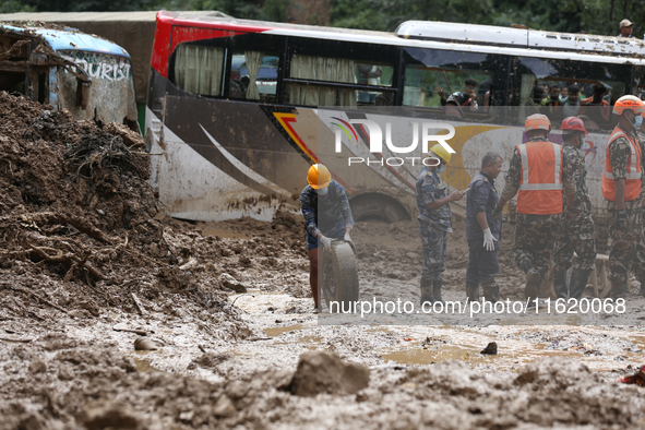 Nepal's Armed Police Force (APF) personnel roll out the remains of a passenger bus from the disaster site in Jhyaple Khola of Dhading Distri...