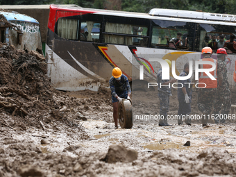 Nepal's Armed Police Force (APF) personnel roll out the remains of a passenger bus from the disaster site in Jhyaple Khola of Dhading Distri...