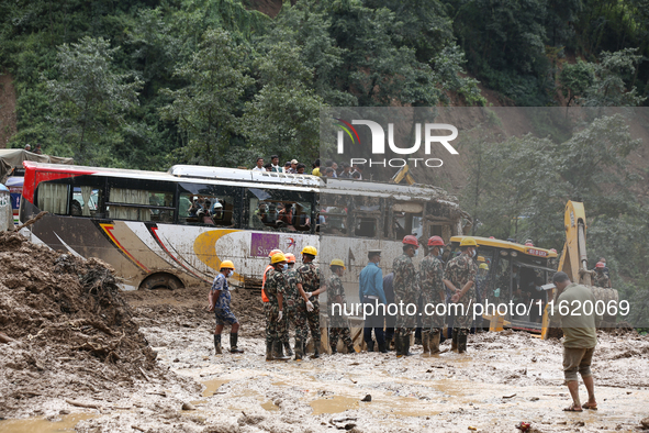 Personnel from Nepal's security agencies, the Nepal Army, Armed Police Force, and the Nepal Police continue a search operation at a landslid...