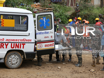 Personnel from Nepal's security agencies, the Nepal Army, Armed Police Force, and the Nepal Police transfer a body into the hearse at a land...