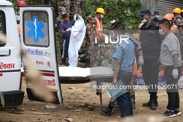 Personnel from Nepal's security agencies, the Nepal Army, Armed Police Force, and the Nepal Police transfer a body into the hearse at a land...