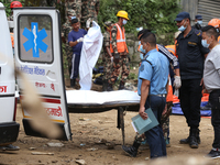 Personnel from Nepal's security agencies, the Nepal Army, Armed Police Force, and the Nepal Police transfer a body into the hearse at a land...