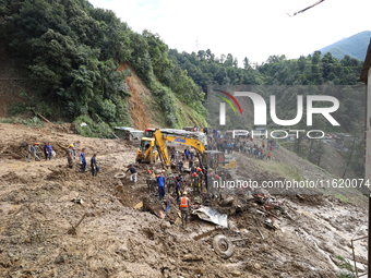 Personnel from Nepal's security agencies, the Nepal Army, Armed Police Force, and the Nepal Police continue a search operation at a landslid...