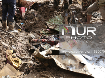 Personnel from Nepal's security agencies, the Nepal Army, Armed Police Force, and the Nepal Police recover a body from a landslide disaster...