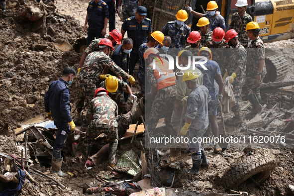 Personnel from Nepal's security agencies, the Nepal Army, Armed Police Force, and the Nepal Police recover a body from a landslide disaster...