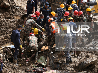 Personnel from Nepal's security agencies, the Nepal Army, Armed Police Force, and the Nepal Police recover a body from a landslide disaster...