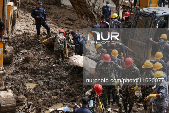 Personnel from Nepal's security agencies, the Nepal Army, Armed Police Force, and the Nepal Police recover a body from a landslide disaster...