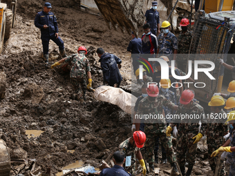 Personnel from Nepal's security agencies, the Nepal Army, Armed Police Force, and the Nepal Police recover a body from a landslide disaster...