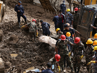 Personnel from Nepal's security agencies, the Nepal Army, Armed Police Force, and the Nepal Police recover a body from a landslide disaster...