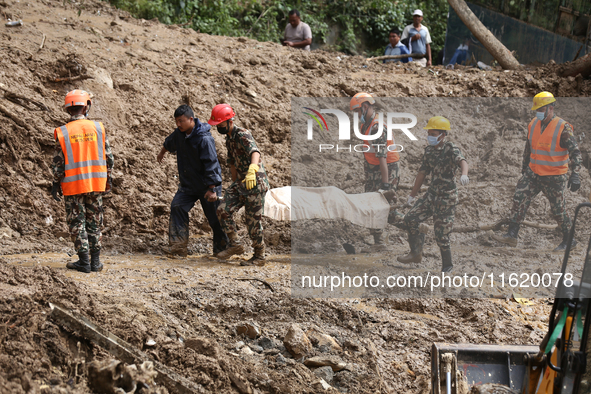 Personnel from Nepal's security agencies, the Nepal Army, Armed Police Force, and the Nepal Police recover a body from a landslide disaster...