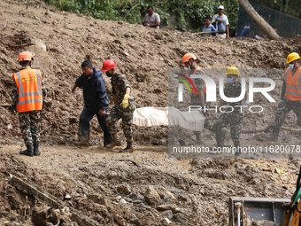 Personnel from Nepal's security agencies, the Nepal Army, Armed Police Force, and the Nepal Police recover a body from a landslide disaster...