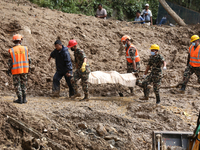 Personnel from Nepal's security agencies, the Nepal Army, Armed Police Force, and the Nepal Police recover a body from a landslide disaster...