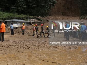 Nepal Army personnel carry the body of a passenger retrieved from the landslide site in Jhyaple Khola in Dhading district of Central Nepal o...