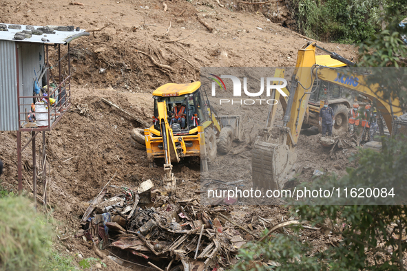 Excavators comb through the mud in search of bodies of passengers believed to be buried in the landslide that covers multiple vehicles at Jh...