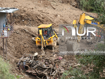 Excavators comb through the mud in search of bodies of passengers believed to be buried in the landslide that covers multiple vehicles at Jh...