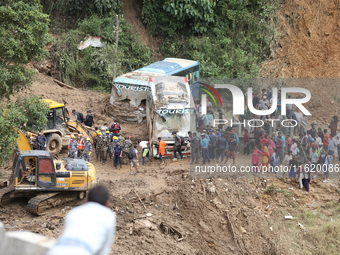 Stranded passengers cross a landslide in Jhyaple Khola in Dhading District of Central Nepal on September 29, 2024. At least 35 people are co...