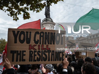 A protester holds a sign reading "you cannot kill the resistance" during a demonstration in support of Lebanese people as intense Israeli at...