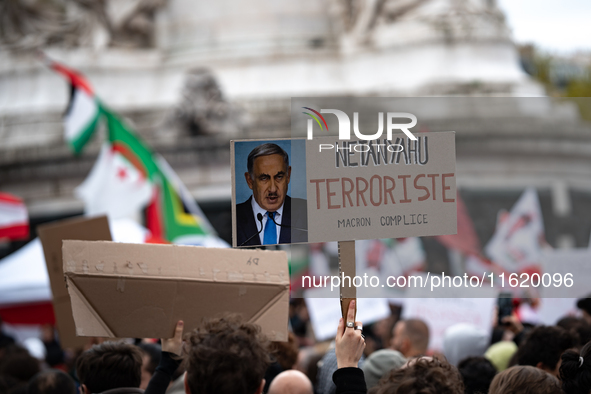 A protester holds a sign reading "Netanyahu terrorist, Macron accomplice" during a demonstration in support of Lebanese people as intense Is...