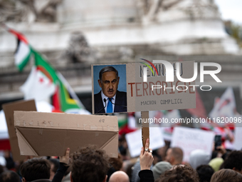 A protester holds a sign reading "Netanyahu terrorist, Macron accomplice" during a demonstration in support of Lebanese people as intense Is...