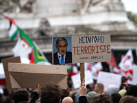 A protester holds a sign reading "Netanyahu terrorist, Macron accomplice" during a demonstration in support of Lebanese people as intense Is...