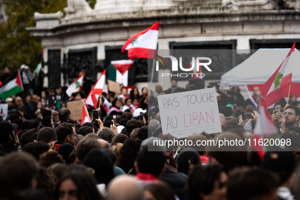 A protester holds a sign reading "Hands off Lebanon" during a demonstration in support of Lebanese people as intense Israeli attacks across...