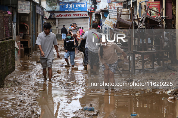 People wade through a muddy road section in Imadol, Lalitpur, Nepal, on September 29, 2024, after heavy rain triggers waterlogging in the ar...