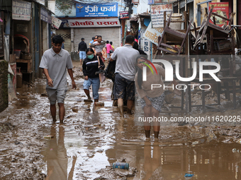 People wade through a muddy road section in Imadol, Lalitpur, Nepal, on September 29, 2024, after heavy rain triggers waterlogging in the ar...