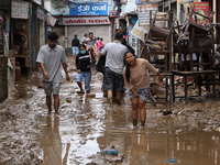 People wade through a muddy road section in Imadol, Lalitpur, Nepal, on September 29, 2024, after heavy rain triggers waterlogging in the ar...