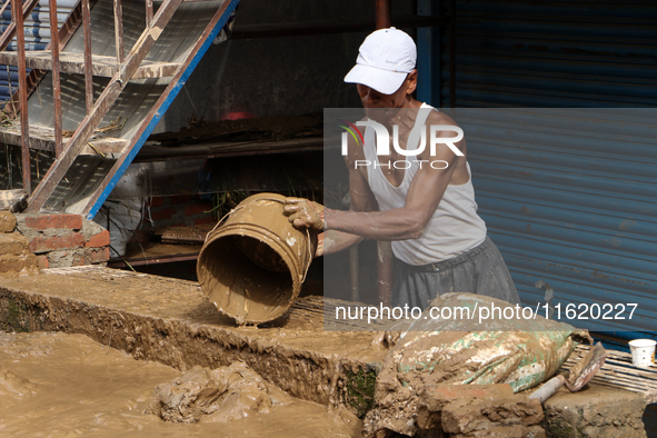 A man throws out muddy water from his home after heavy rain triggers waterlogging in the area in Nepal on September 29, 2024. A day earlier,...