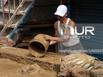 A man throws out muddy water from his home after heavy rain triggers waterlogging in the area in Nepal on September 29, 2024. A day earlier,...