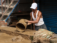 A man throws out muddy water from his home after heavy rain triggers waterlogging in the area in Nepal on September 29, 2024. A day earlier,...