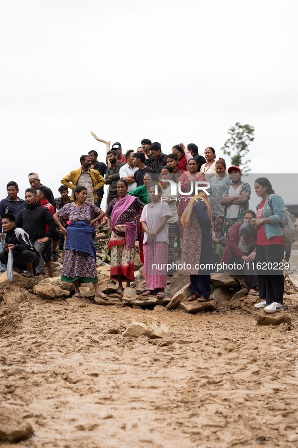 Spectators and relatives watch as the rescue teams conduct search operations at Jhyaple Khola in Dhading District, Nepal, on September 29, 2...