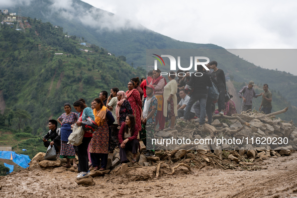 Spectators and relatives watch as the rescue teams conduct search operations at Jhyaple Khola in Dhading District, Nepal, on September 29, 2...