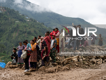 Spectators and relatives watch as the rescue teams conduct search operations at Jhyaple Khola in Dhading District, Nepal, on September 29, 2...