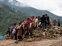 Spectators and relatives watch as the rescue teams conduct search operations at Jhyaple Khola in Dhading District, Nepal, on September 29, 2...