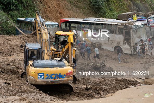 People cross the landslide area at Jhyaple Khola, Dhading District, Nepal, on September 29, 2024, after passenger buses are buried in a land...