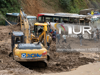 People cross the landslide area at Jhyaple Khola, Dhading District, Nepal, on September 29, 2024, after passenger buses are buried in a land...