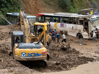 People cross the landslide area at Jhyaple Khola, Dhading District, Nepal, on September 29, 2024, after passenger buses are buried in a land...