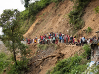 Family members wait to identify the recovered bodies of bus passengers buried in a landslide in Jhyaple Khola, Dhading District, Nepal, on S...