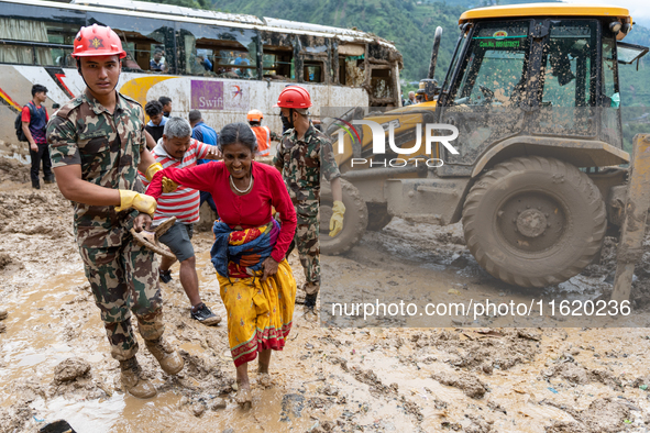 People cross the landslide area at Jhyaple Khola, Dhading District, Nepal, on September 29, 2024, after passenger buses are buried in a land...