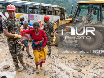 People cross the landslide area at Jhyaple Khola, Dhading District, Nepal, on September 29, 2024, after passenger buses are buried in a land...