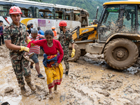 People cross the landslide area at Jhyaple Khola, Dhading District, Nepal, on September 29, 2024, after passenger buses are buried in a land...