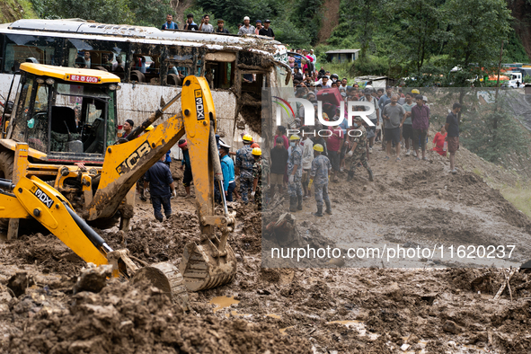 People cross the landslide area at Jhyaple Khola, Dhading District, Nepal, on September 29, 2024, after passenger buses are buried in a land...