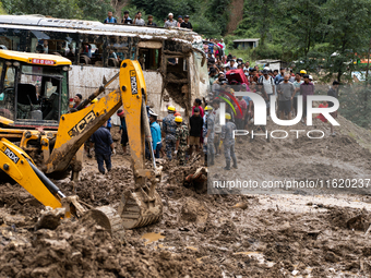 People cross the landslide area at Jhyaple Khola, Dhading District, Nepal, on September 29, 2024, after passenger buses are buried in a land...