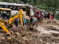 People cross the landslide area at Jhyaple Khola, Dhading District, Nepal, on September 29, 2024, after passenger buses are buried in a land...