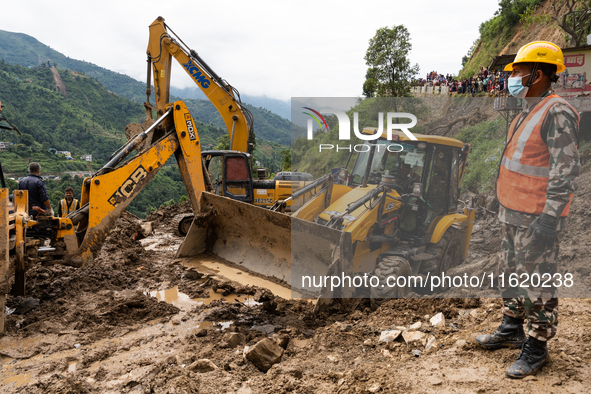 Rescue teams conduct search operations at Jhyaple Khola, Dhading District, Nepal, on September 29, 2024, after passenger buses are buried in...