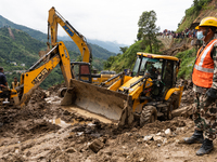 Rescue teams conduct search operations at Jhyaple Khola, Dhading District, Nepal, on September 29, 2024, after passenger buses are buried in...